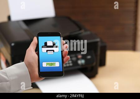 Man using printer management application on mobile phone indoors, closeup and space for text Stock Photo