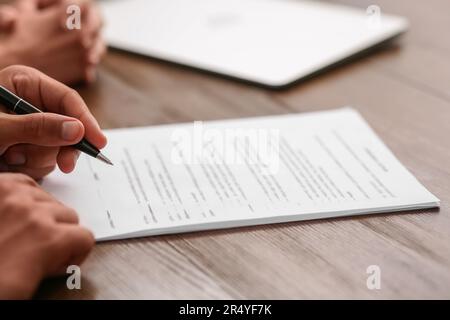 Notary helping couple with paperwork at wooden table, closeup Stock Photo
