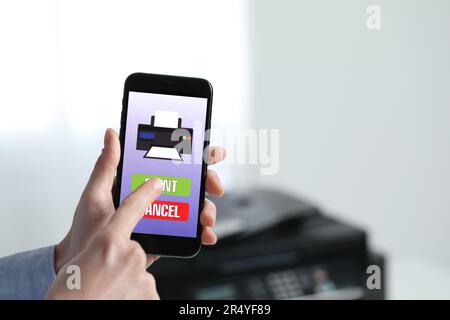 Man using printer management application on mobile phone indoors, closeup and space for text Stock Photo