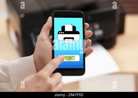 Man using printer management application on mobile phone indoors, closeup. Image on device screen. Stock Photo