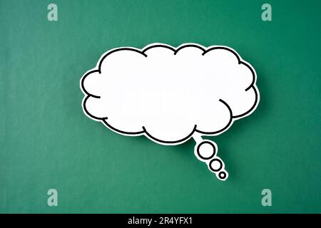White speech bubble shaped post it note on green background with copy space. Stock Photo