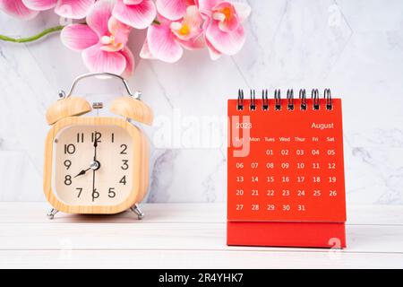 Red calendar August 2023. Desk calendar for year 2023 and pink orchid on wooden background. Stock Photo
