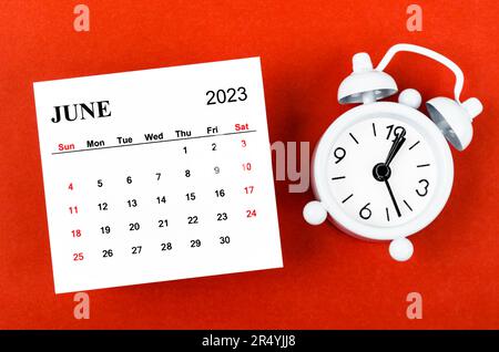 June 2023 Monthly calendar year with alarm clock on red background. Stock Photo