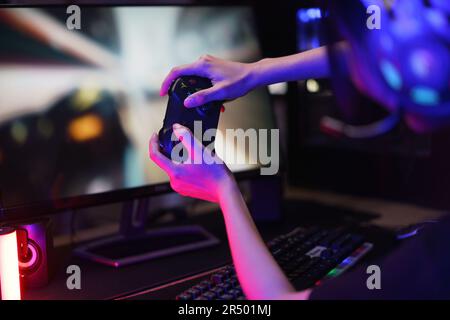 Female cyber hacker gamer use joystick to competition and playing games on computer in neon light. Stock Photo