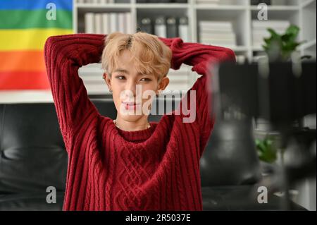 Portrait of an attractive young Asian gay influencer or blogger filming his blog or broadcasting live through his smartphone at home. Stock Photo
