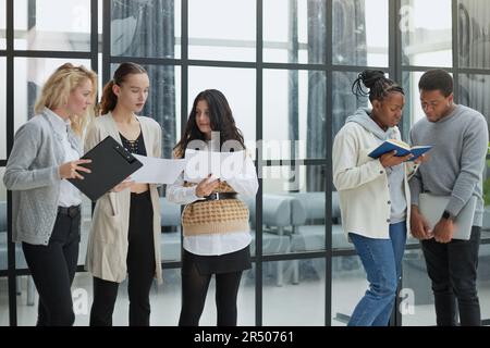 Serious people are holding a folder and writing on papers while colleagues Stock Photo