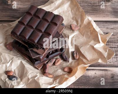 Cocoa beans and chocolate that contains them, selective focus. Chocolate bars on the wooden table Stock Photo