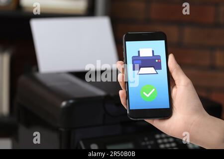 Man using printer management application on mobile phone indoors, closeup and space for text Stock Photo