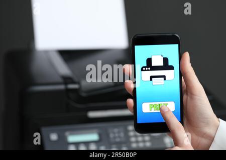 Man using printer management application on mobile phone indoors, closeup and space for text Stock Photo
