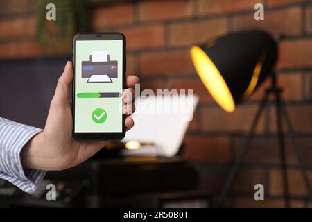 Man using printer management application on mobile phone indoors, closeup and space for text Stock Photo