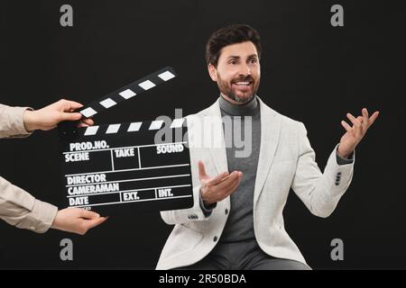 Actor performing while second assistant camera holding clapperboard on black background Stock Photo