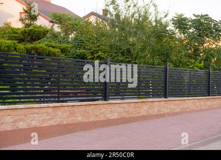 House and trees behind beautiful fence outdoors Stock Photo