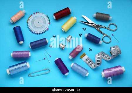 Flat lay composition with thimbles and different sewing tools on light blue background Stock Photo