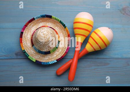 Colorful maracas and sombrero hat on light blue wooden table, flat lay. Musical instrument Stock Photo