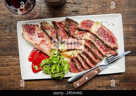 Rare slices of steak served with a glass of red wine Stock Photo