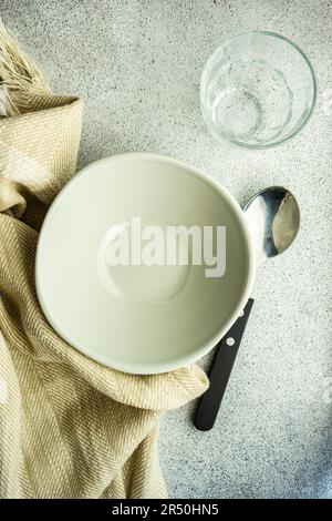 Minimalistic table setting with rustic napkin and stoneware on concrete table Stock Photo