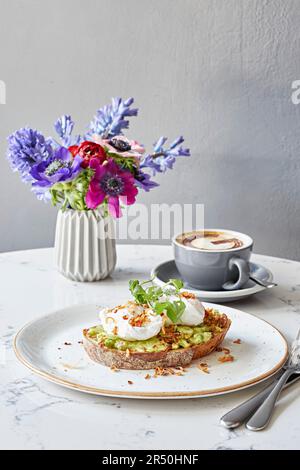 Poached eggs on mashed avocado and sourdough toast Stock Photo
