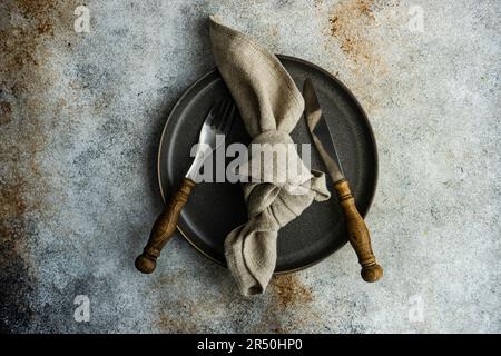 Minimalistic table setting with rustic napkin and stoneware on concrete table Stock Photo