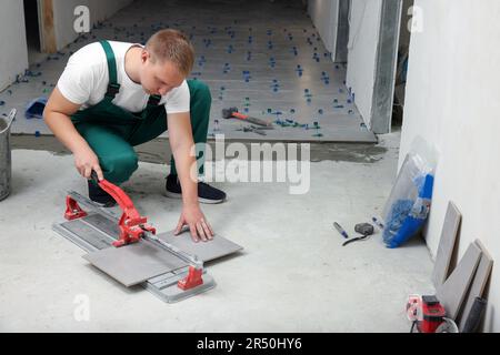 Worker using manual tile cutter in room Stock Photo
