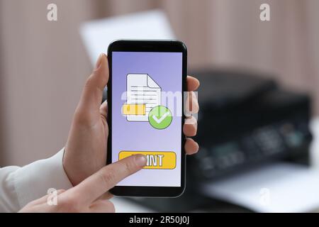 Man using printer management application on mobile phone in office, closeup Stock Photo