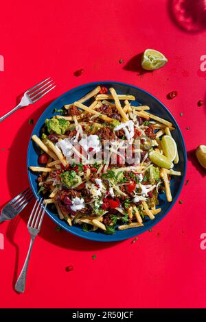 Loaded nacho fries with Mexican spiced beef, salsa, cheese, guacamole, sour cream and lime Stock Photo