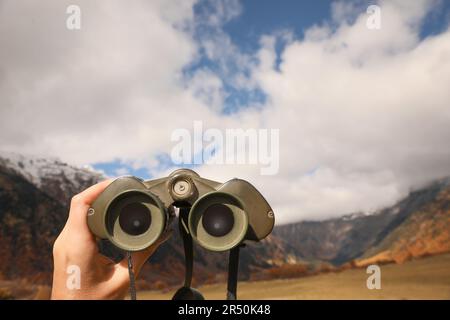 Boy holding binoculars in beautiful mountains, closeup. Space for text Stock Photo