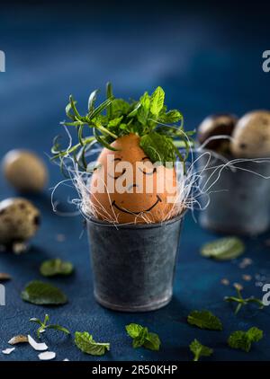 Breakfast egg with a face and herbs in an Easter egg cup Stock Photo