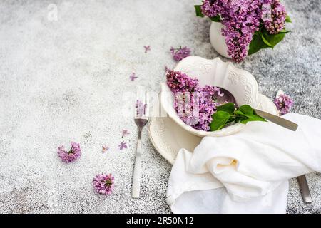 Spring place setting with lilac flowers on outdoor table Stock Photo