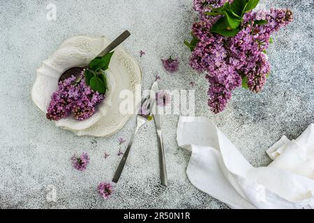 Spring place setting with lilac flowers on outdoor table Stock Photo