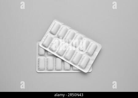 Blisters with chewing gums on grey background, flat lay Stock Photo