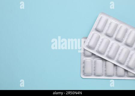 Blisters with chewing gums on light blue background, flat lay. Space for text Stock Photo