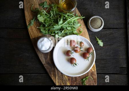 Cherry tomatoes and rocket on wooden board Stock Photo