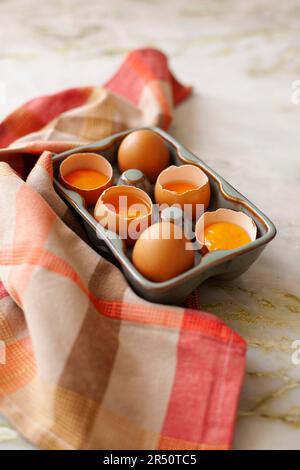 Fresh eggs, partially cracked, in an egg container Stock Photo