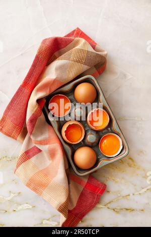 Fresh eggs, partially cracked, in an egg container Stock Photo