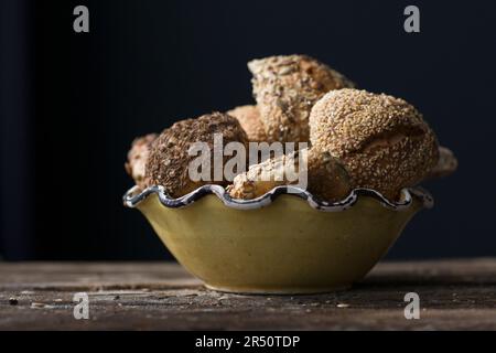 Assorted grain rolls in a bowl on a black background Stock Photo