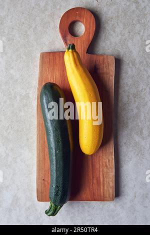 Yellow summer squash and green zucchini on a wooden board Stock Photo