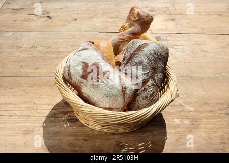 Various freshly baked goods in a basket on a wooden table Stock Photo