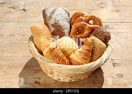 Assorted fresh baked goods in basket on wooden table Stock Photo