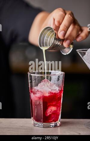 Making Cosmopolitan cocktail, pouring lime juice in a glass Stock Photo