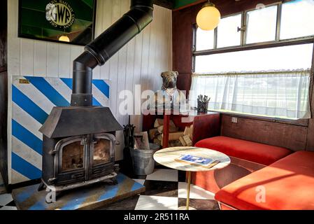 Interior of an unusual conversion of train carriages to a cafe and diner with wood burning fireplace and vintage objects. England UK Stock Photo