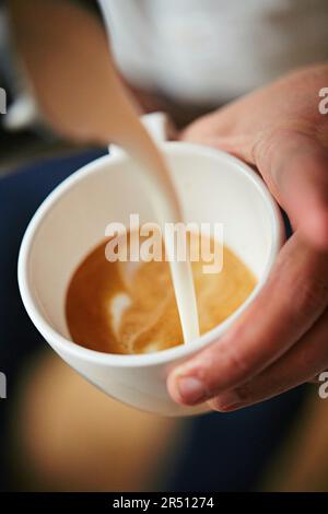 Barista pouring a flat wite with latte art Stock Photo