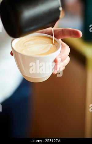 Barista pours milk foam to make latte art Stock Photo