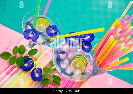 Drinks with ice cubes, limes, straws and flowers by the pool Stock Photo