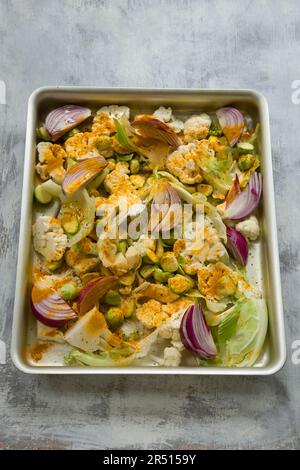 Cauliflower florets with red onions and turmeric in a roasting tin Stock Photo