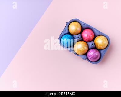 Colourful Easter eggs in an egg carton on a pink background Stock Photo