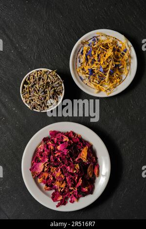 Rose petals, lavender flowers and mixed flowers on plate and slate plate Stock Photo