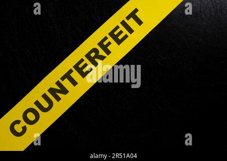 Counterfeit product and item caution and warning concept. Yellow barricade tape with word in dark black background. Stock Photo