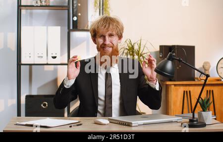 Young businessman working on laptop computer, meditating, doing yoga breathing exercise in lotus position at home office. Calm serene freelancer man taking break. Busy occupation. Peace of mind Stock Photo