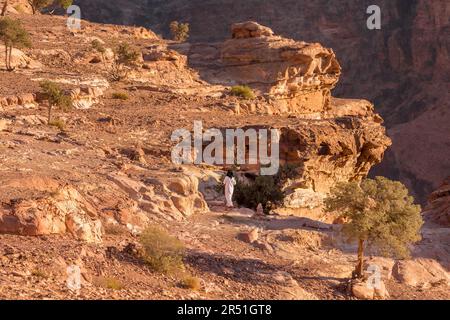 Petra, Jordan - November 3, 2022: Bedouin man walking in sandstone canyon, rocks formations landscape Stock Photo