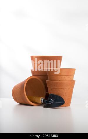 Clay pots and mini shovel on white wooden table. Stock Photo